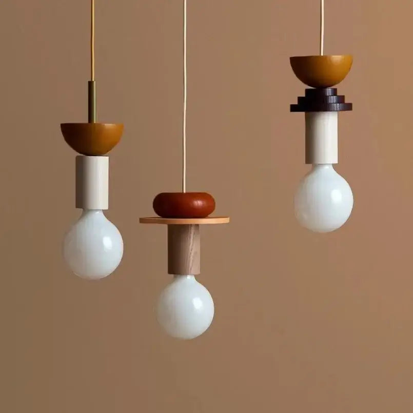 Three minimalist pendant lights with white glass bulbs and colorful nordic wood and ceramic earth tone fixtures for dining room decorbites