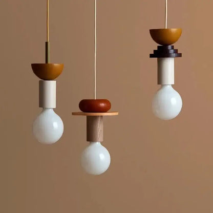 Three minimalist pendant lights with white glass bulbs and colorful nordic wood and ceramic earth tone fixtures for dining room decorbites
