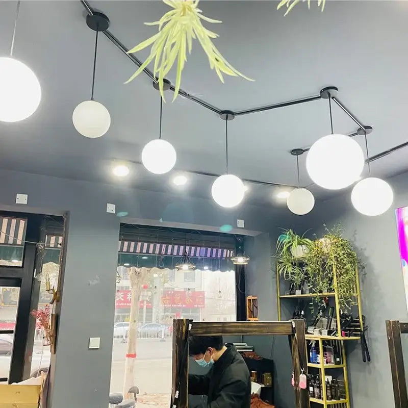 Minimalist spherical pendant light with frosted white acrylic globe and black metal fixtures for dining room lighting