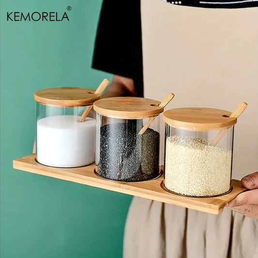 Set of three clear glass spice jars with bamboo lids and wooden spoons for minimalist kitchen organization