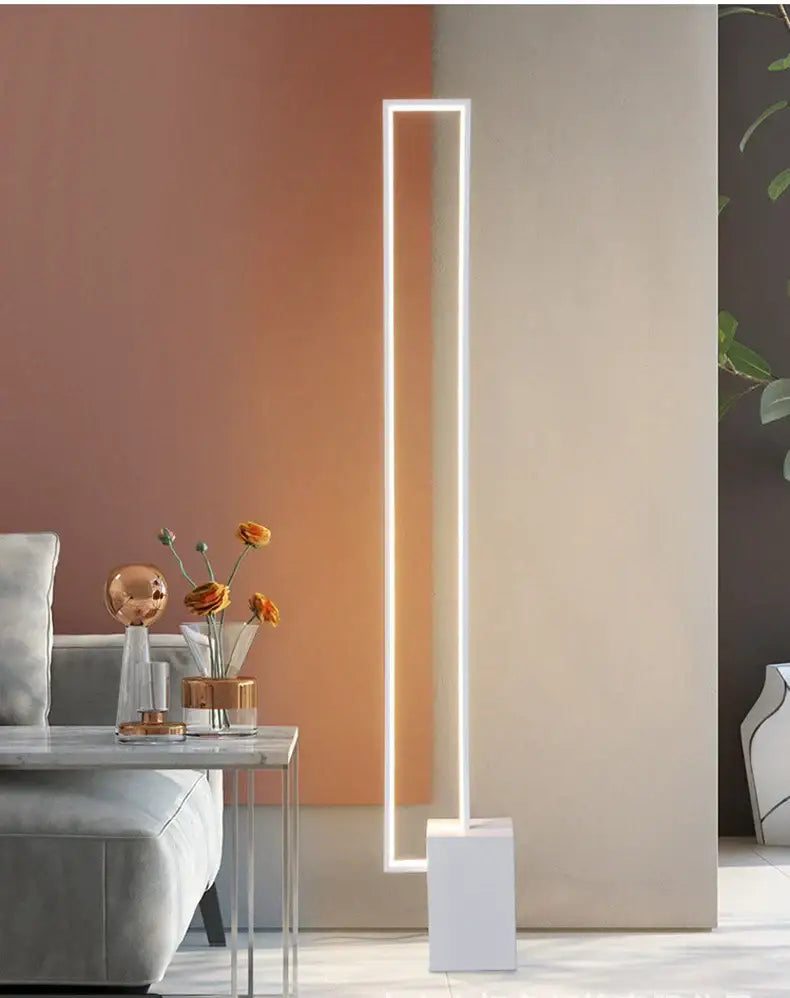 A minimalist gold and black geometric led floor lamp with a glowing white strip on a thin metal frame decorbites floor lamp