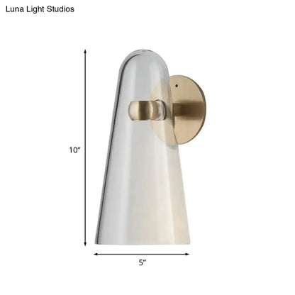 A sleek minimalist gold and clear acrylic wall mount lighting sconce with a translucent glass shade and brushed brass accents