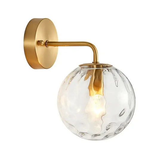 Minimalist gold ball sconce with hammered glass shade and brass hardware featuring a textured clear globe