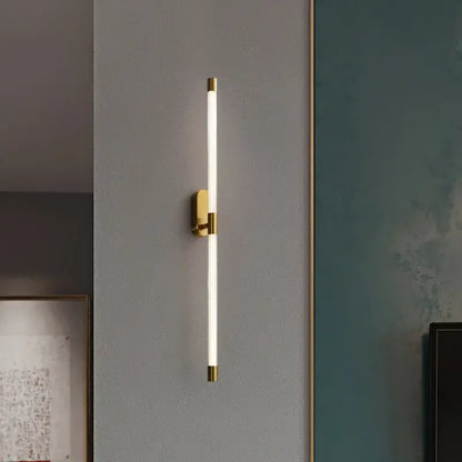 A modern minimalist gold and black decorbites acrylic line led wall light with a gold metal frame and soft white illumination