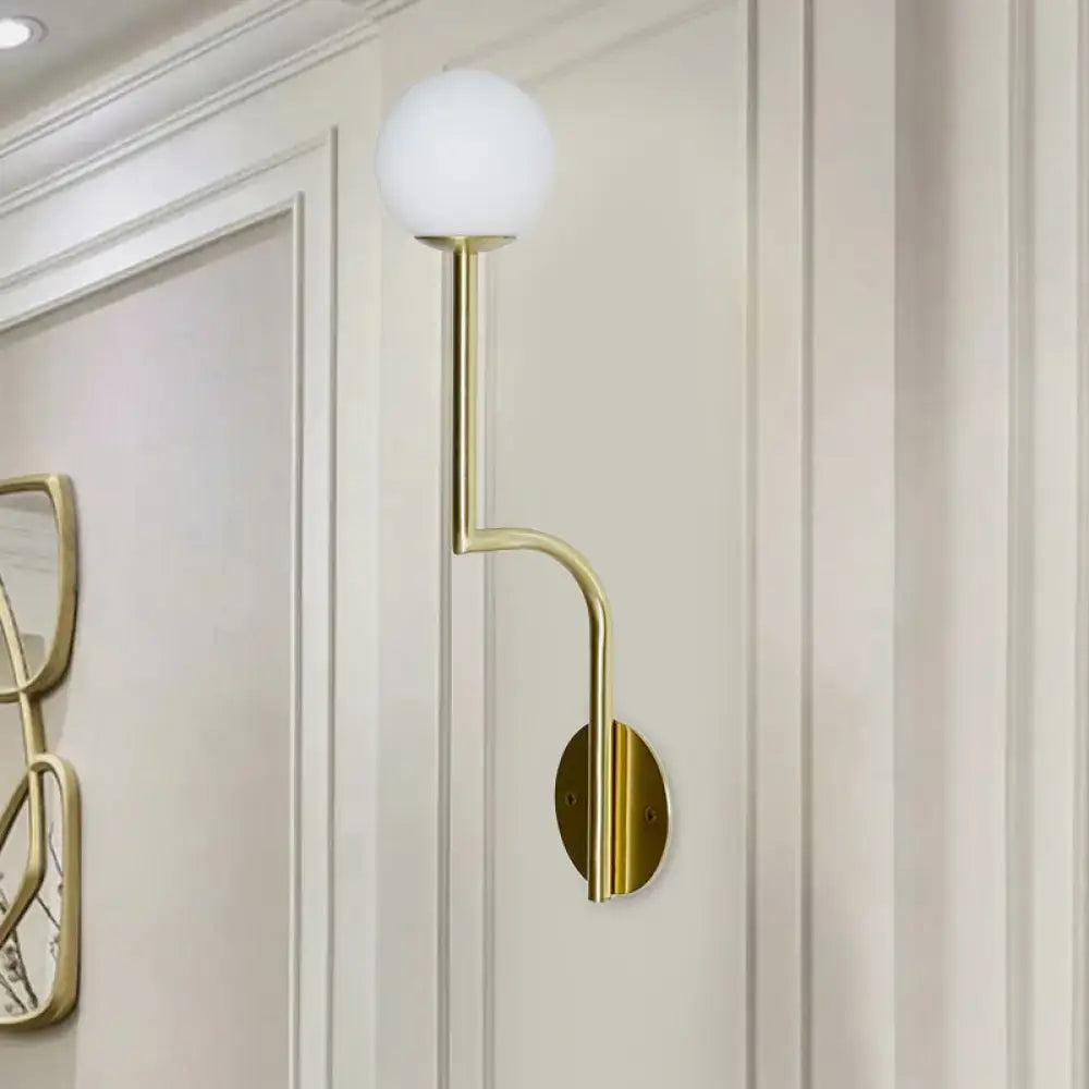 Minimalist gold-toned wall sconce with frosted opal glass globe and long curved arm for bedroom lighting