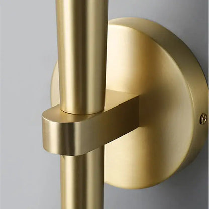 Brass-finished wall sconce with sleek intersecting rods and circular backplate for decorbites crystal minimalist bedroom light
