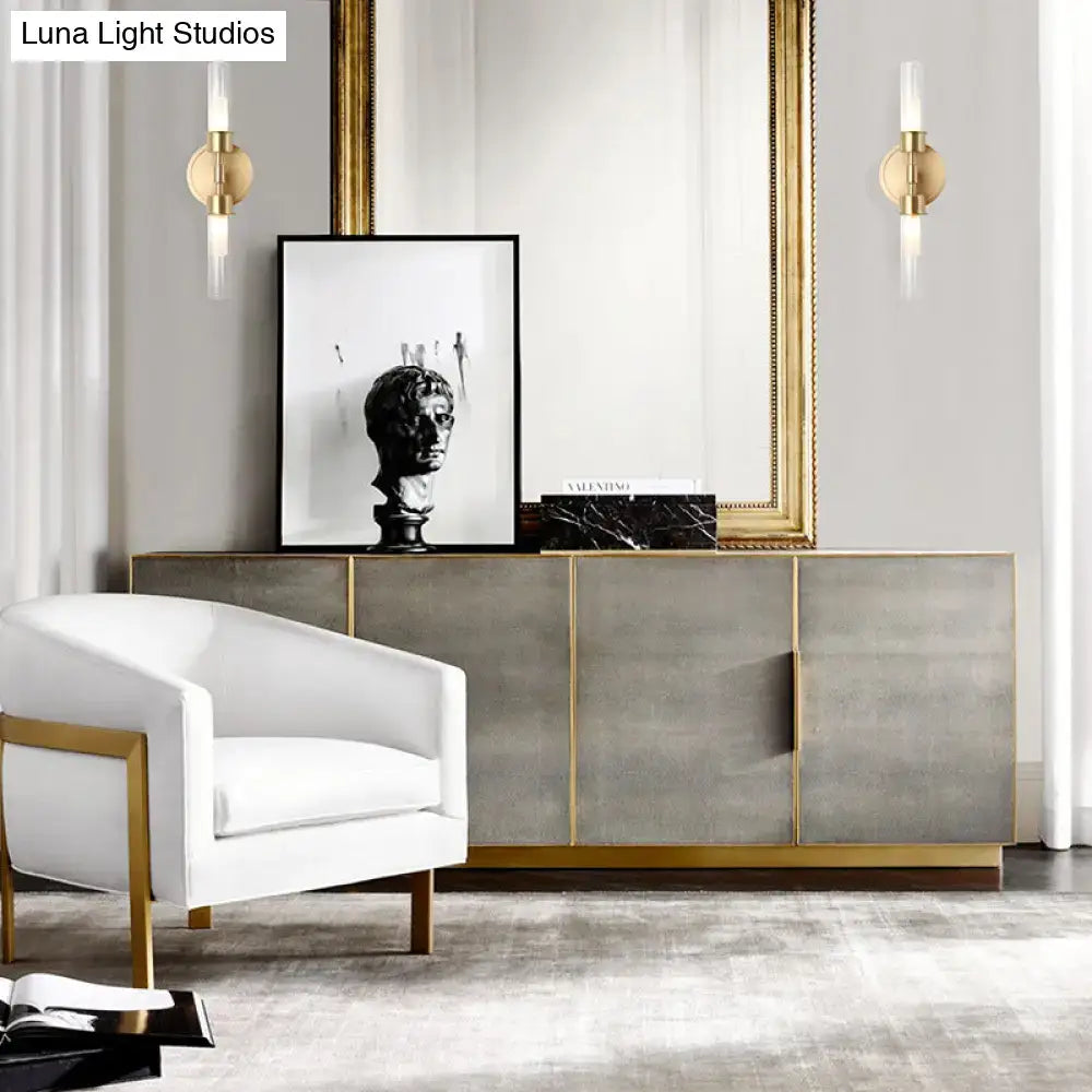 White armchair with gold metal frame next to a minimalist gold double cylinder 2 light inch fixture for bedroom wall