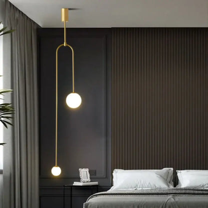 Minimalist gold-toned pendant light with double head glass balls suspended by a curved metal arm for bedroom use