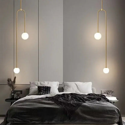 Gold-toned minimalist double head glass ball pendant lights with frosted spherical shades hanging above the bed