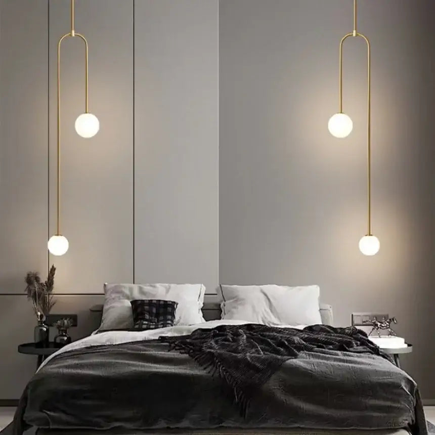 Gold-toned minimalist double head glass ball pendant lights with frosted spherical shades hanging above the bed