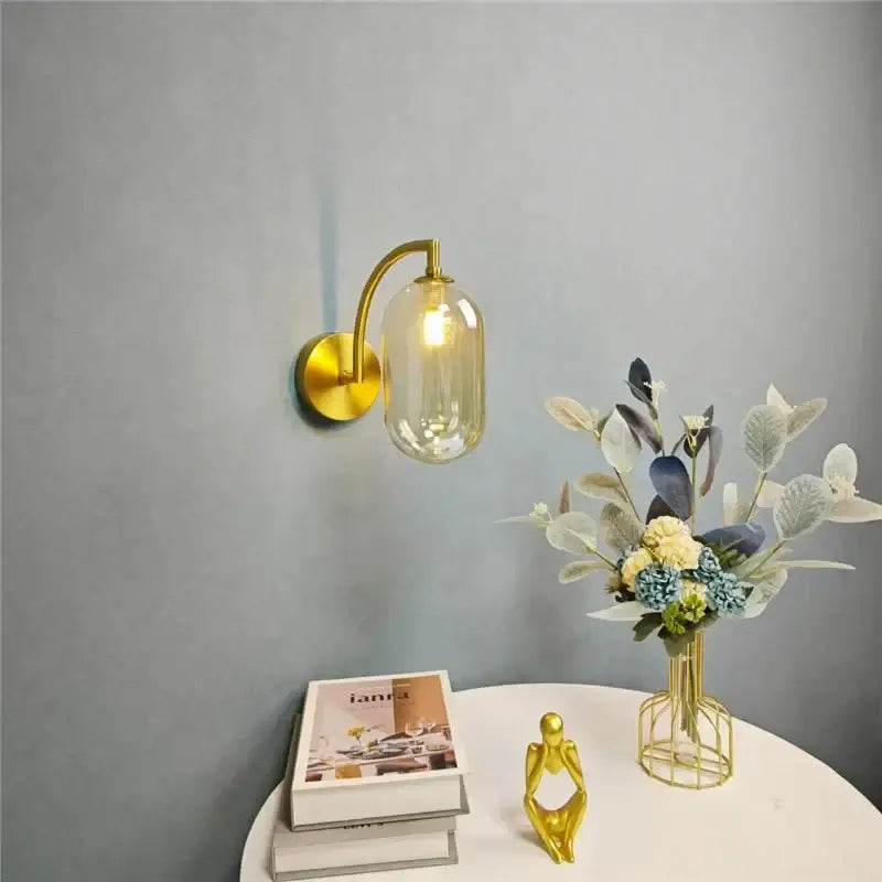Minimalist gold wall sconce with curved arm and translucent amber glass ball shade for bedroom wall lamp
