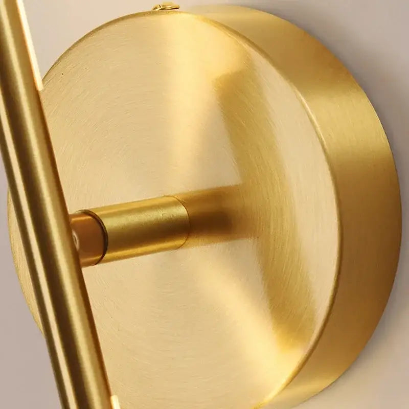 Minimalist gold wall sconce lamps in brass with sleek circular base and slender vertical arm for bathroom lighting