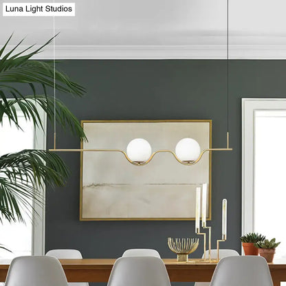 Minimalist gold metal island pendant ceiling light with modern brass fixture and two white glass globes for dining table