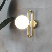 Minimalist gold oval arm wall light with cream matte glass and a sleek curved frame for bedroom sconce lighting
