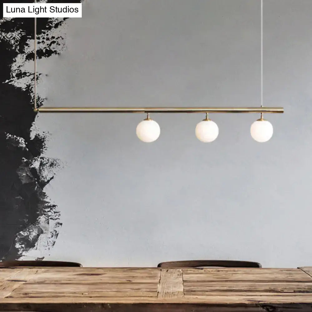 DecorBites™ modern brass bar pendant light with three white glass globes for dining room illumination