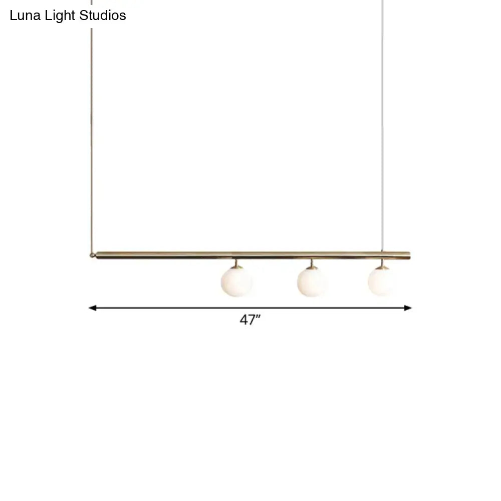 Modern minimalist DecorBites™ dining room pendant light with sleek brass bar and three frosted glass globe bulbs