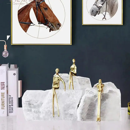Three slender golden man sculptures on white crystal bookends for minimalist home decor by decorbites golden man