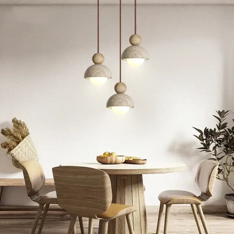 Three gray matte concrete pendant lights with glass ball accents hang above a wooden dining table decorbites glass ball pendant light