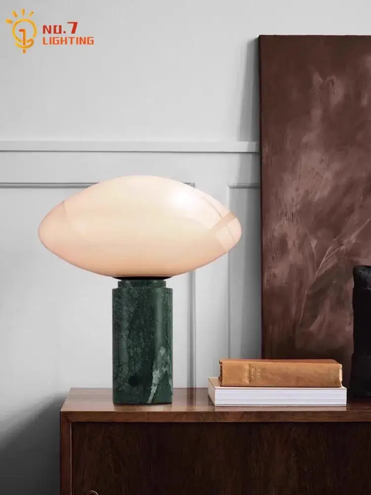 A minimalist green marble led table lamp with a peach glass shade and dark green decorbites green marble base
