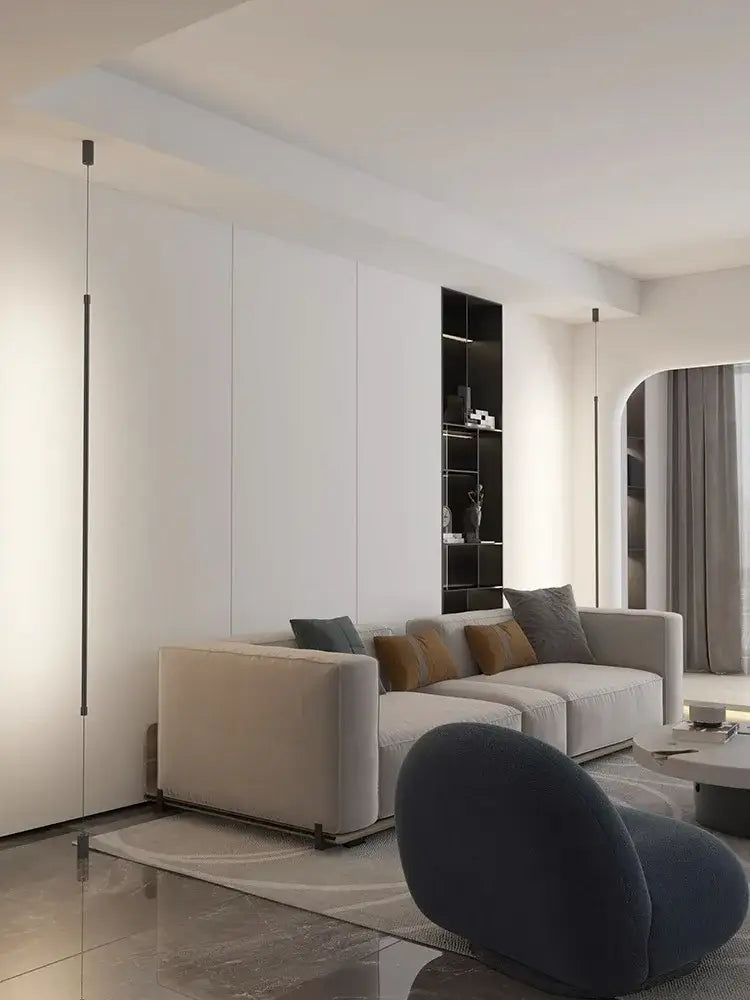 Modern beige sectional sofa with plush cushions and sleek metal legs beneath minimalist matte black cylindrical pendant light strip