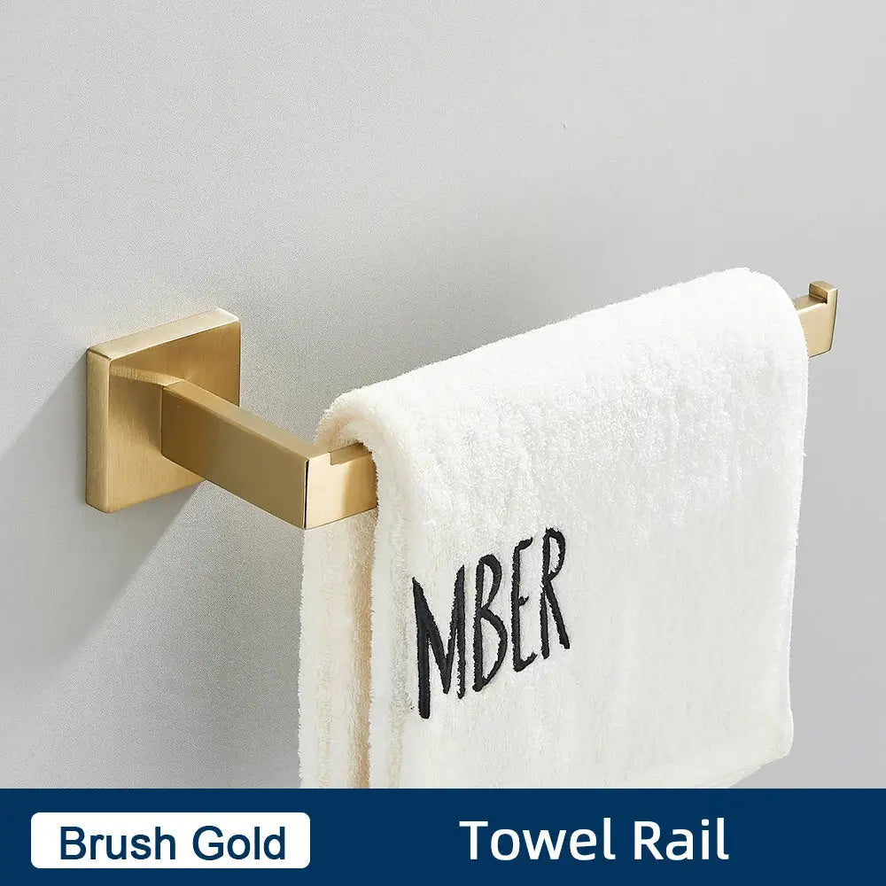Brushed gold towel rail holding white towel with black embroidered lettering in minimalist matte black stainless steel bathroom accessories set