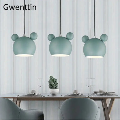 Three mint green minimalist matte cartoon mouse pendant lights hang above a dining table decorbites pendant light