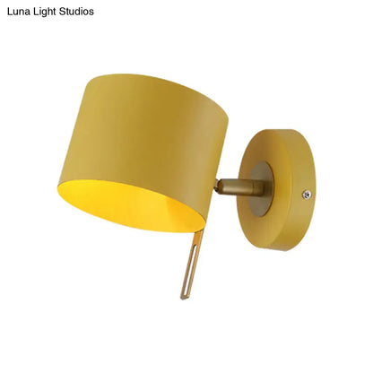 Minimalist yellow cylindrical wall sconce with matte finish and brass accents for corridor lighting with pink hues