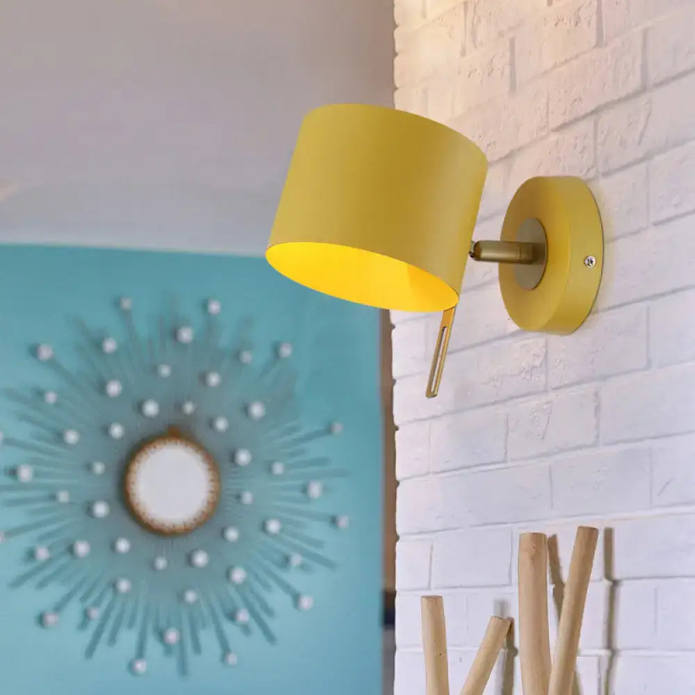 Minimalist yellow cylindrical wall sconce with matte finish and brass arm for corridor lighting with pink accents