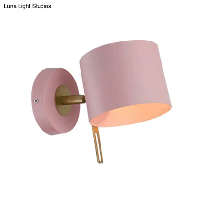 Minimalist pink and brass cylinder wall sconce with pastel pink shade and brass mounting for corridor lighting with pink yellow accents