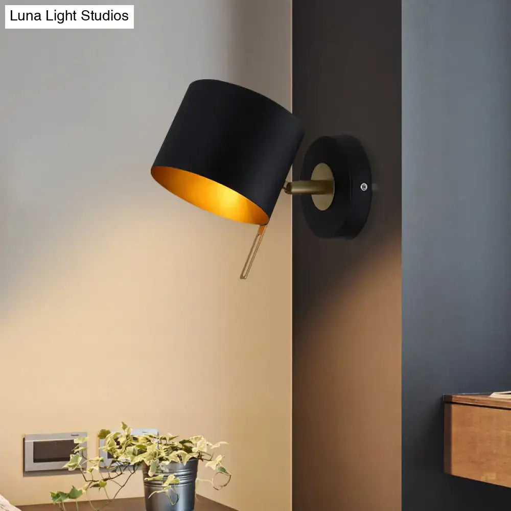 Minimalist black cylindrical wall sconce with gold interior and brass accents for corridor lighting with pink yellow tones