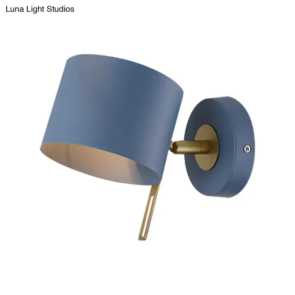 Blue cylindrical wall sconce with brass-finished arm and mounting plate for minimalist corridor lighting with pink yellow accents