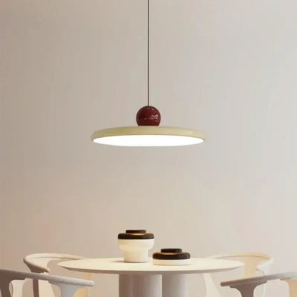 Minimalist red and white acrylic pendant light with glossy spherical top and flat shade suspended by thin cord pendant