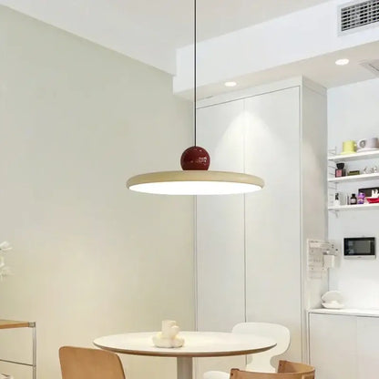 Minimalist red and white acrylic pendant light with a wooden disc and glossy red cord pendant for dining room use