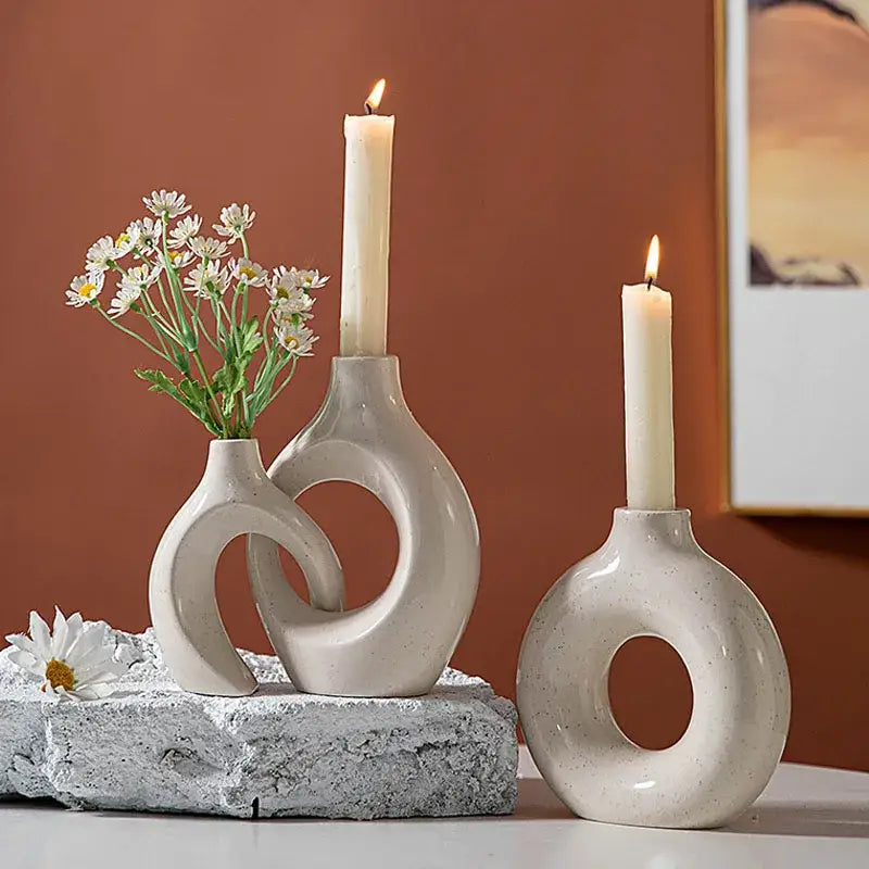 Minimalist speckled off-white ceramic donut candle holder with circular cutouts holding daisies and lit candles for decorbites