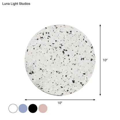 A 10-inch round terrazzo-style white and black speckled coaster complementing minimalist terrazzo round led wall sconce light