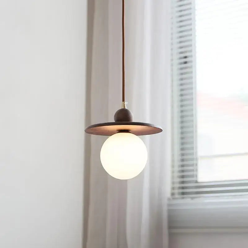 Minimalist walnut and brass glass led pendant lamp with circular disc shade and frosted globe bulb for dining room