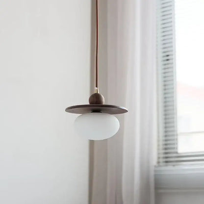 Minimalist walnut and brass glass led pendant lamp with matte white globe dark wood disc shade and copper cord for dining room