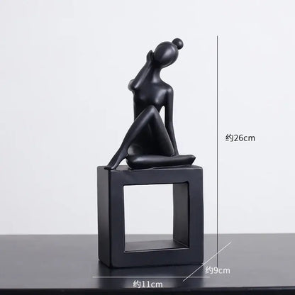 Minimalist black matte abstract figures sculpture of a seated woman with hand raised on a square base for living room decor