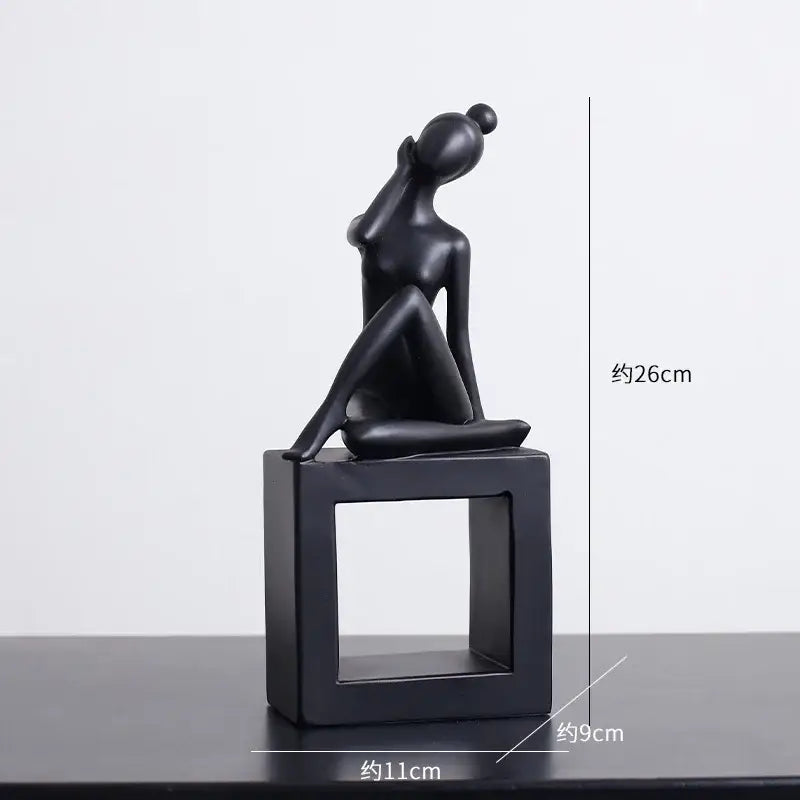 Minimalist black matte abstract figures sculpture of a seated woman with hand raised on a square base for living room decor