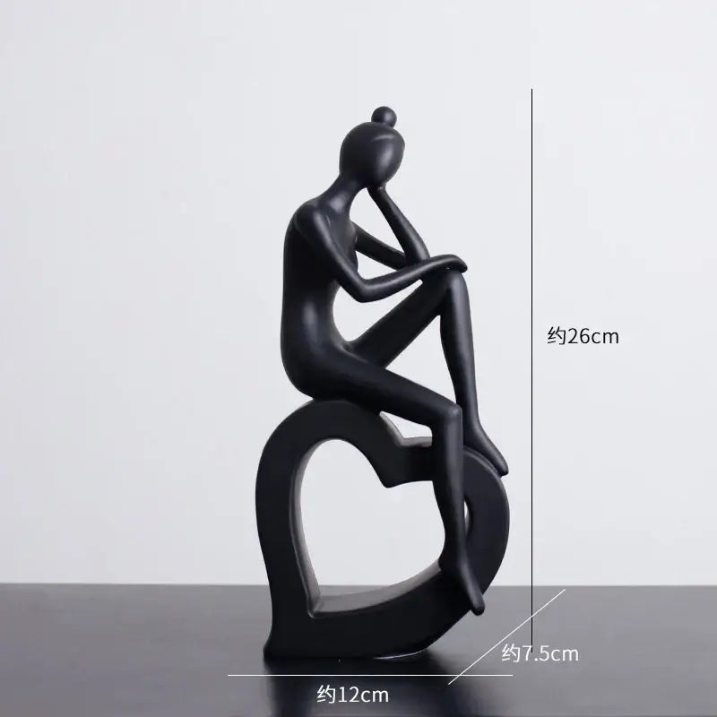 Black glossy resin abstract figures sculpture of a seated figure on a heart-shaped base for living room decor