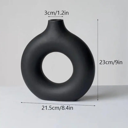 A sleek matte black decorbites ceramic donut vase with modern ring design and smooth rounded contours for minimalist decor