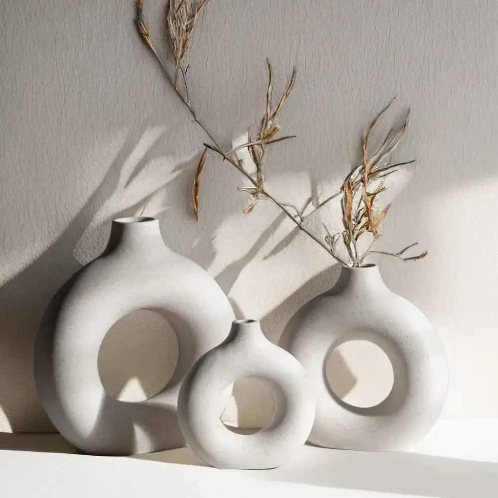 Set of three minimalist white decorbites ceramic donut vases with circular cutouts in varied sizes and shapes for living room