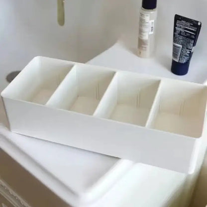White minimalist rectangular divided storage box with four compartments made of smooth plastic for kitchen tableware