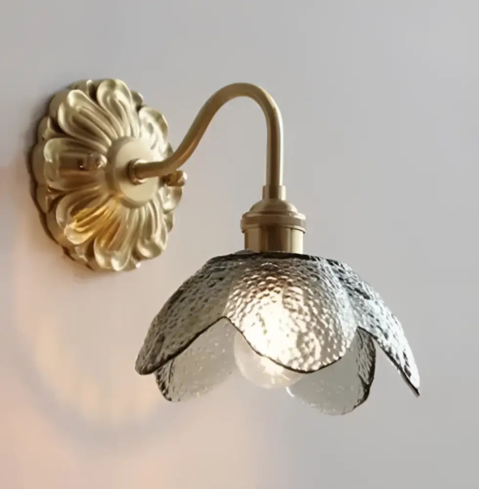 Gold-toned wall sconce with textured translucent glass shade shaped like open flower complements minimalist glass pendant lights for dining room