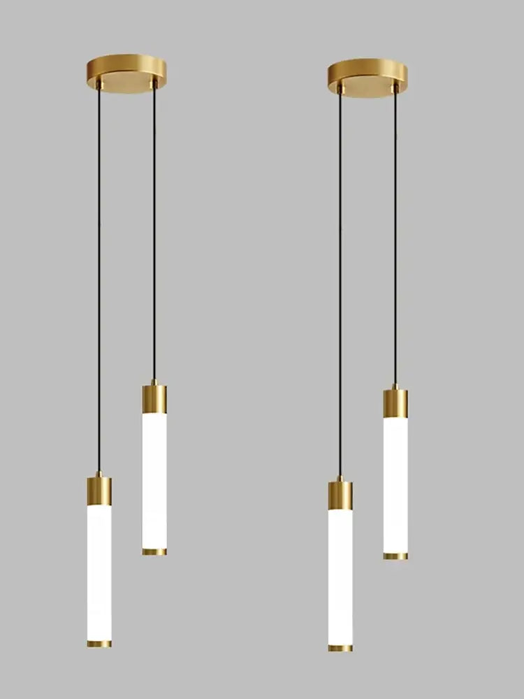 Gold-finished cylindrical pendant light with frosted glass tubes and black cords for minimalist kitchen island lighting