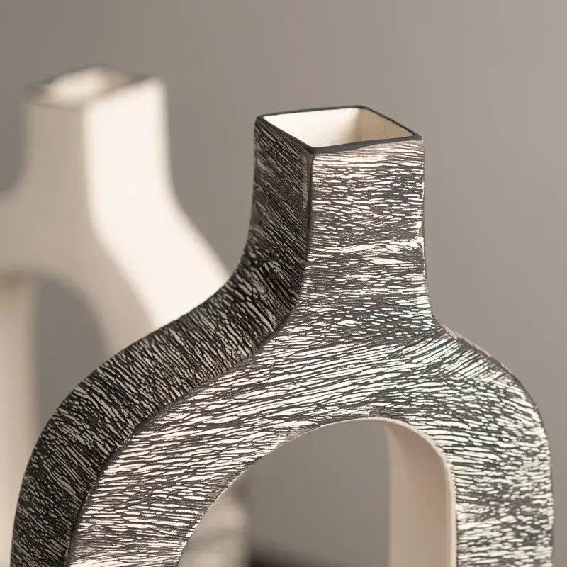 A sleek ceramic flower vase with black and white geometric stripes and an angular neck for living room decor