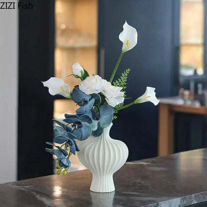 Minimalist white heart shape ceramic vase with vertical ridged texture holding white calla lilies and blue orchids decorbites heart shape decor