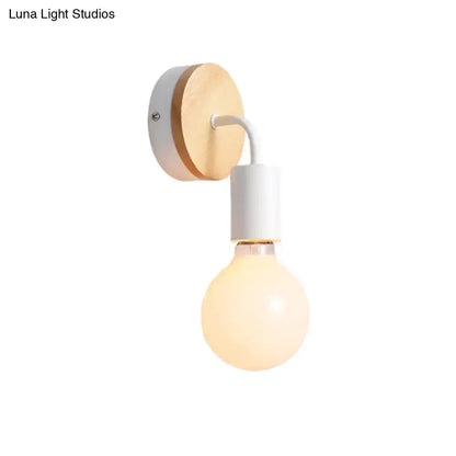 Minimalist bare bulb wall sconce with round wooden backplate and white metal trim for bedroom lighting