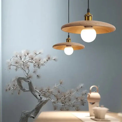 Minimalist wood and brass pendant light with led bulb featuring warm-toned discs and three-color dimming above tea setup