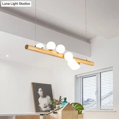 Minimalist linear island pendant with natural wood finish and five frosted glass globe bulbs for kitchen lighting